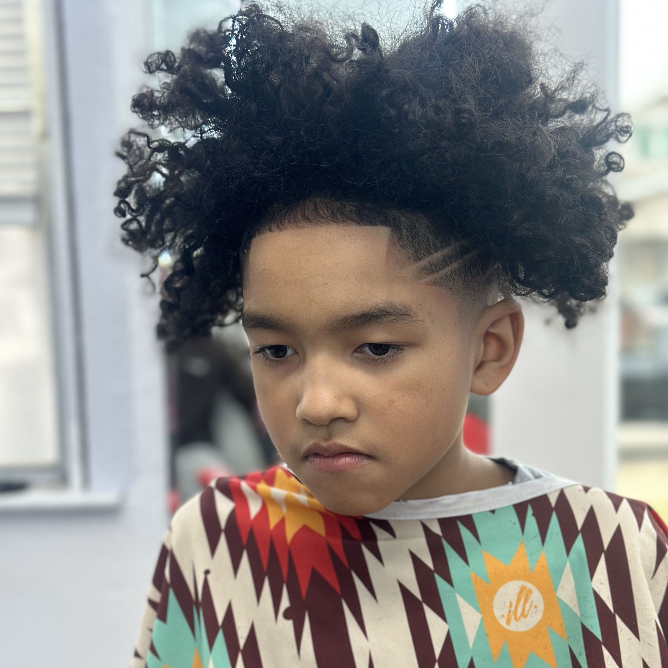Young client with a curly taper and freestyle design at The Luxe